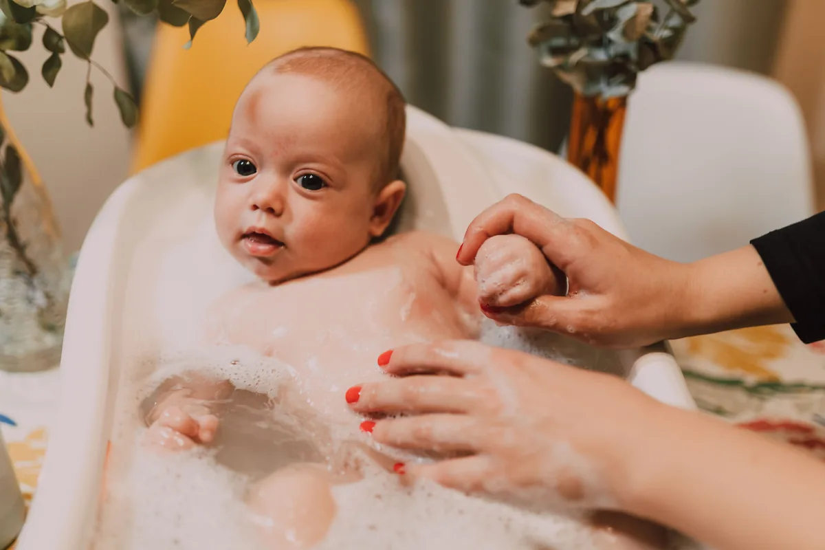 Madre bañando a su bebé en la bañera, con espuma y cariño