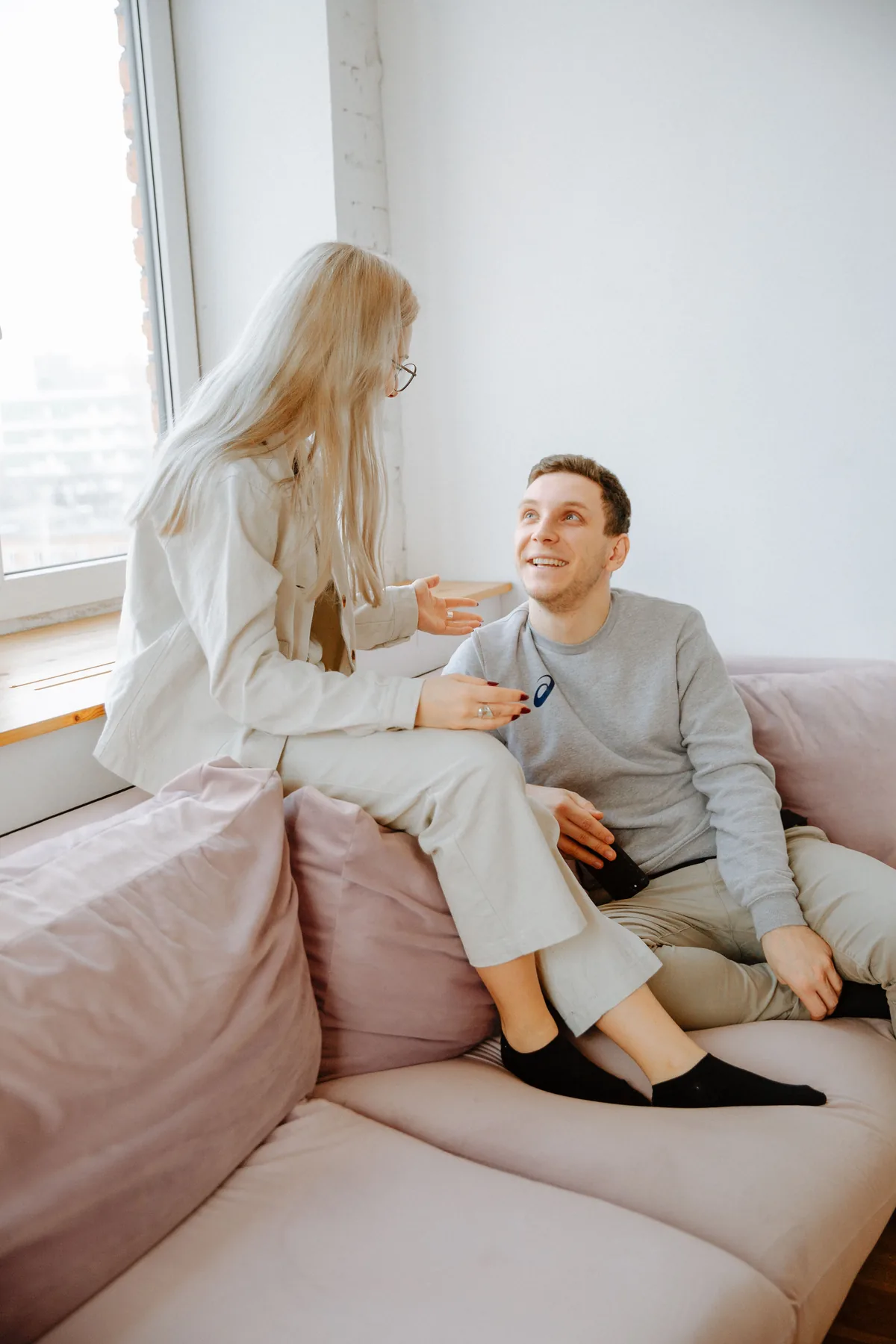 Pareja conversando de forma cercana, cara a cara, con el bebé fuera de foco en segundo plano